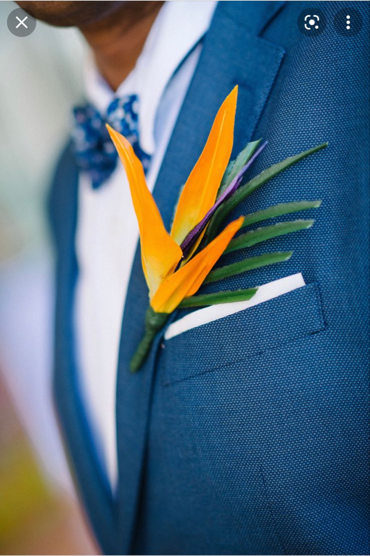 a man wearing a blue suit with an orange flower pinned to his lapel