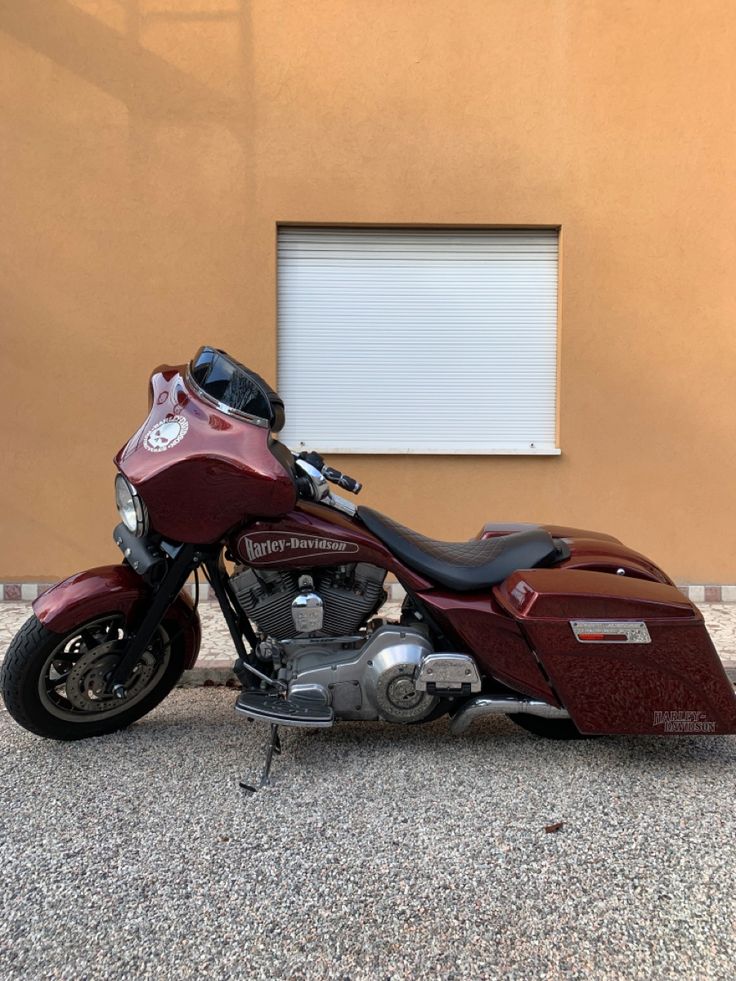 a maroon motorcycle parked in front of a building