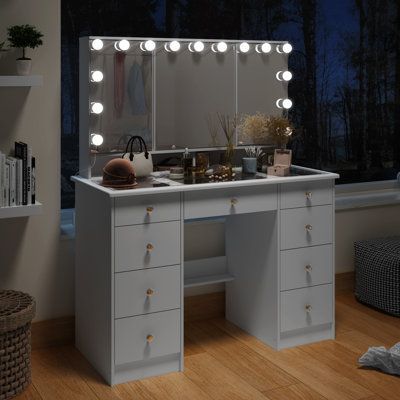 a white vanity with lights on it in front of a window and bookshelf