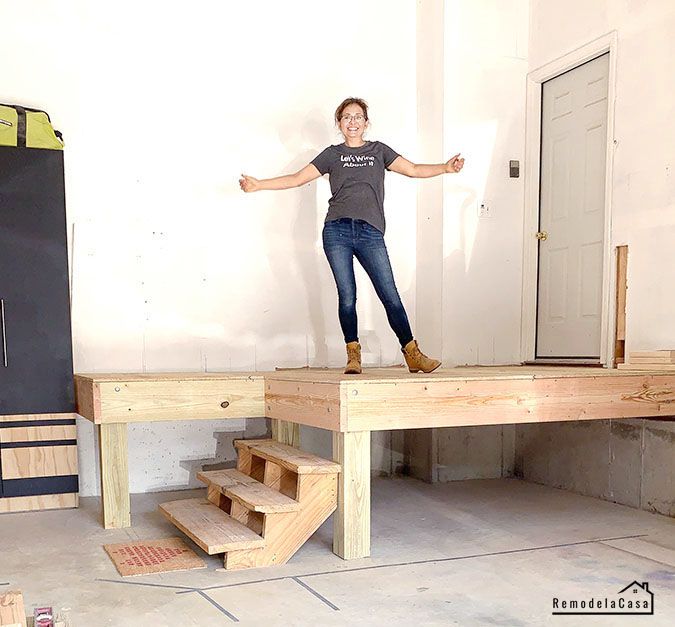 a woman standing on top of a wooden bench in front of a door and stairs