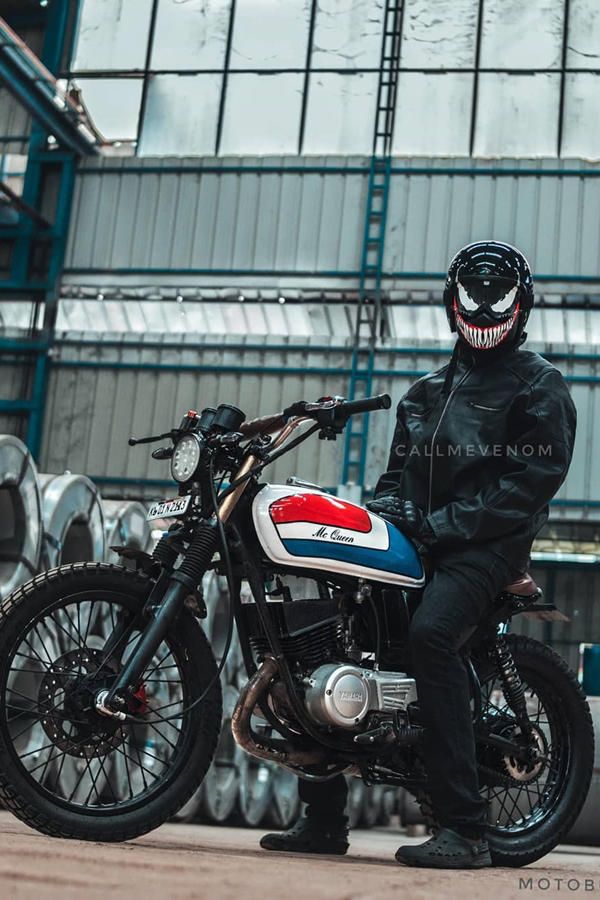 a man sitting on top of a motorcycle in front of a building with lots of pipes