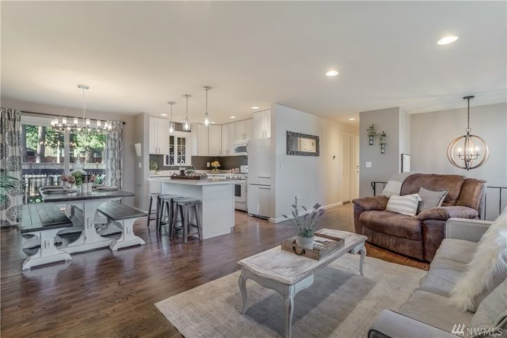 a living room filled with furniture next to a kitchen and dining room table on top of a hard wood floor