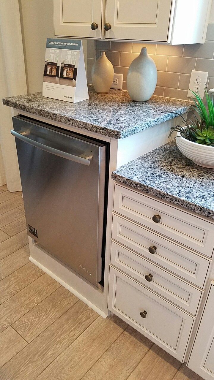 a dishwasher is sitting in the middle of a kitchen counter with white cabinets