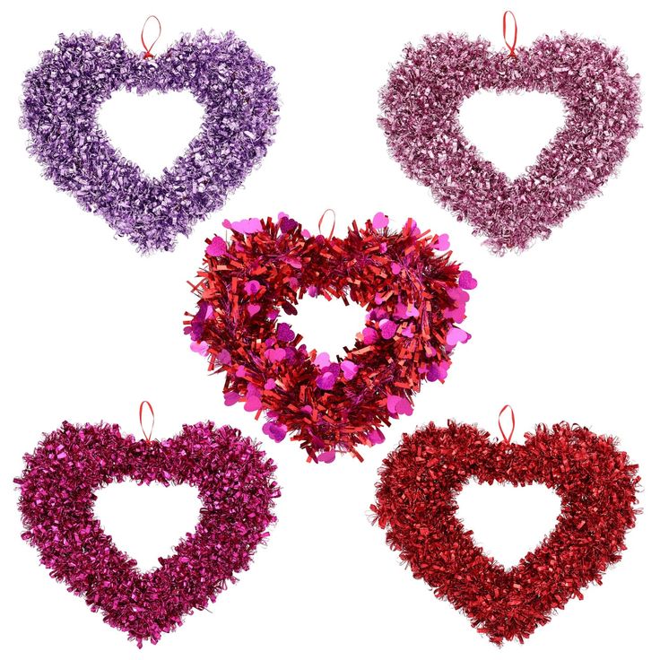 three heart shaped wreaths hanging from strings on a white background with red, purple and pink tinsel