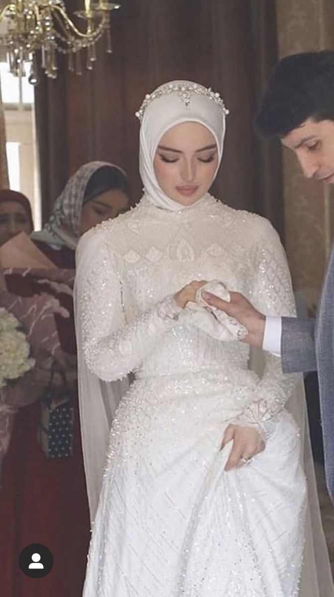 a man standing next to a woman in a white dress and veil on her wedding day