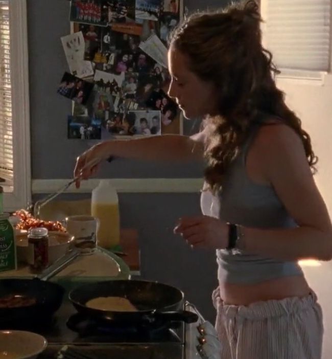 a woman standing in front of a stove cooking food on top of a frying pan