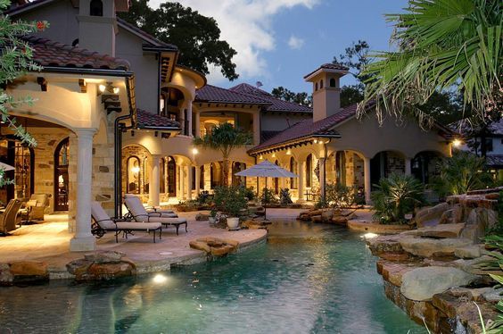 a large house with a pool in front of it and some chairs next to it