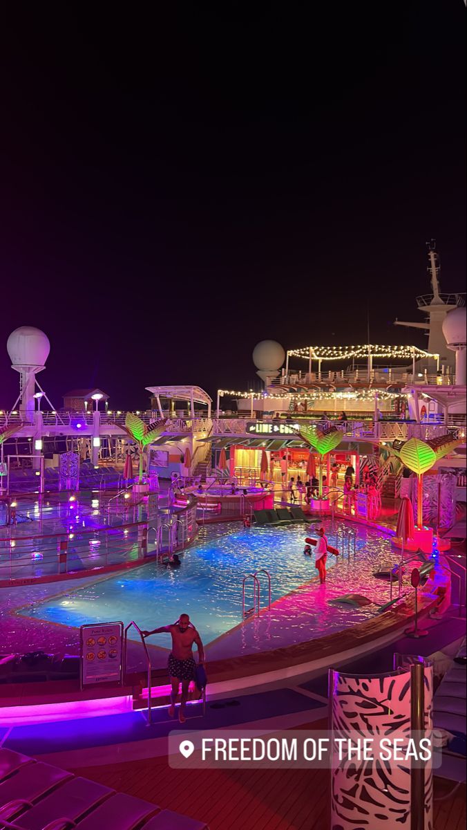 a large pool on the deck of a cruise ship at night with people in it