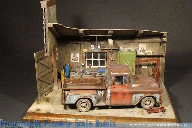 an old rusty truck is parked in front of a building that has a garage on it