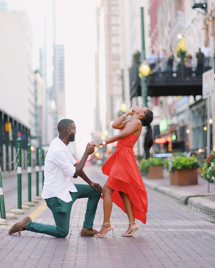 a man kneeling down next to a woman on the street