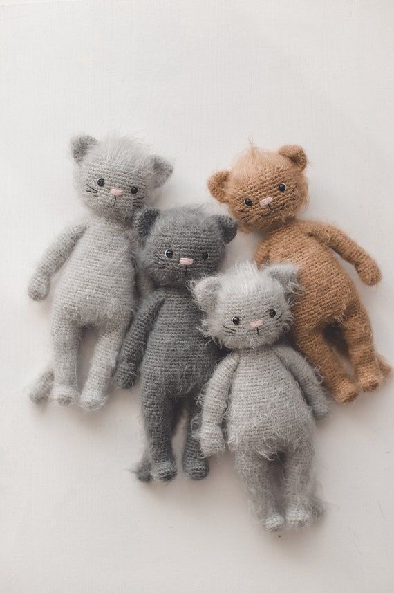 five knitted teddy bears sitting next to each other on a white tablecloth background