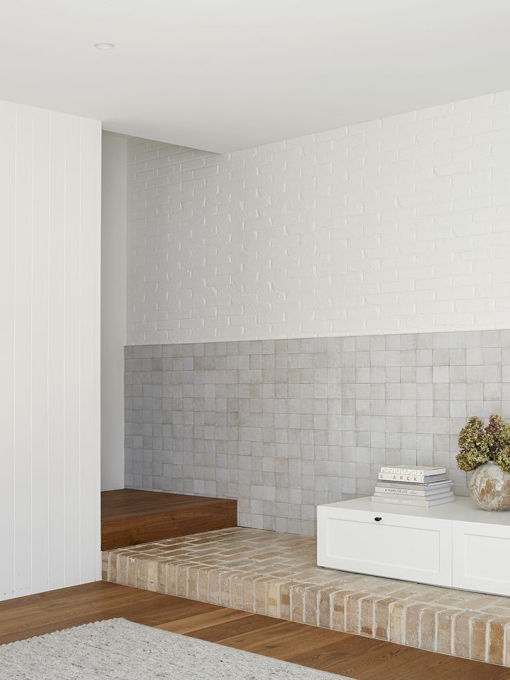 a room with white brick walls and wooden steps leading up to the second floor area