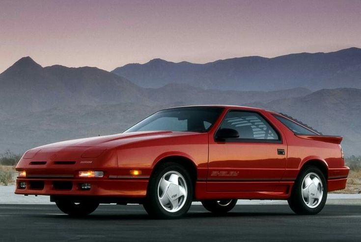 an orange sports car parked in front of mountains