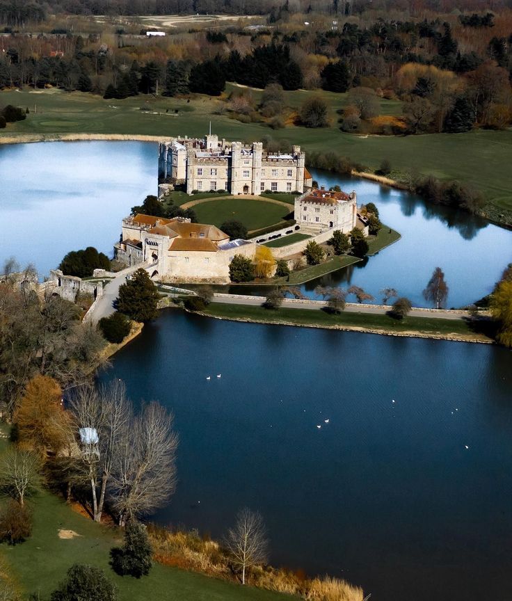 an aerial view of a large castle in the middle of a lake and surrounded by trees