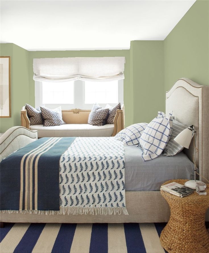 a bed room with a neatly made bed and striped rugs on the floor next to a window