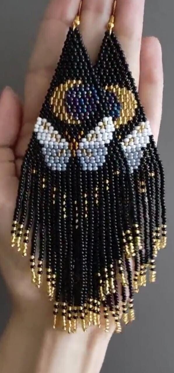 a hand holding a beaded black and gold necklace