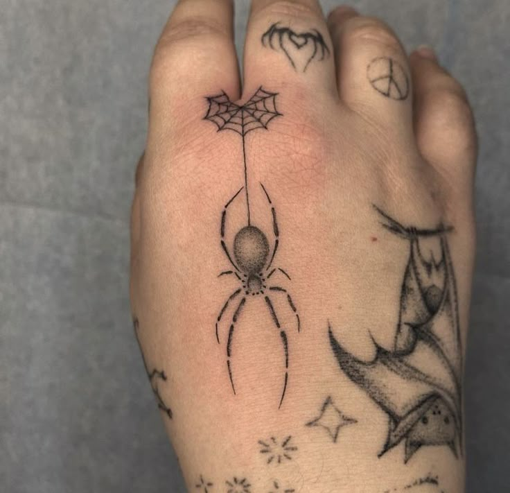 a person's hand with tattoos on it, and a spider tattoo on the wrist