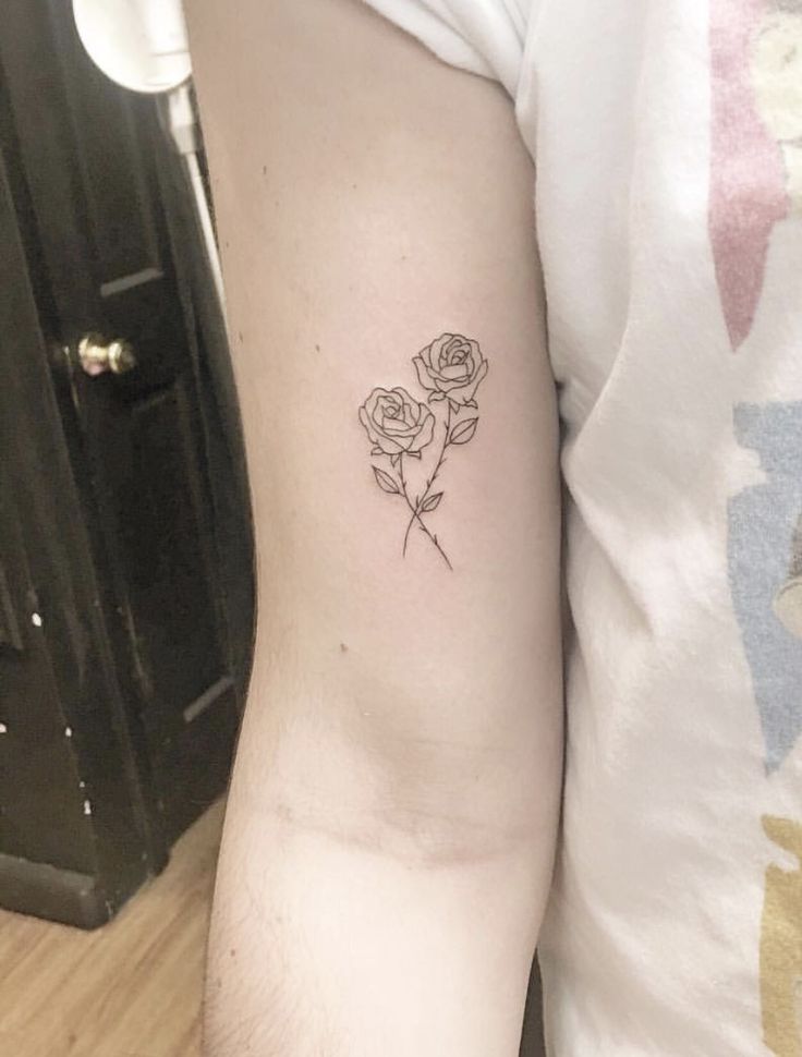 a woman's arm with a single rose tattoo on the left side of her arm