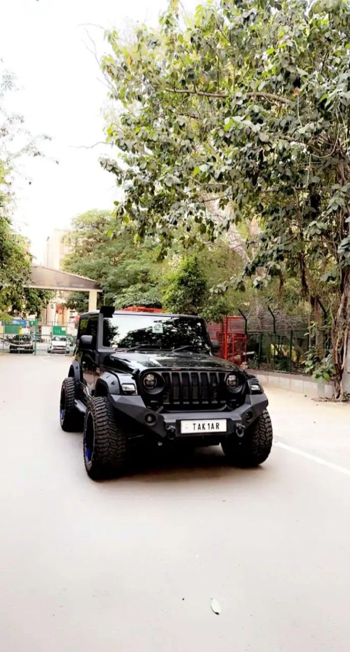 a black jeep driving down a street next to trees