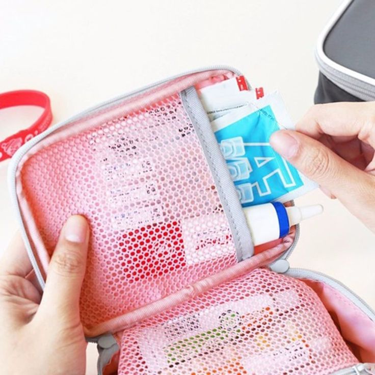 a person holding an open pink case with various items in it on a white table