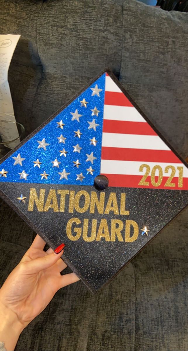 a woman's hand holding up a national guard graduation cap with the american flag on it