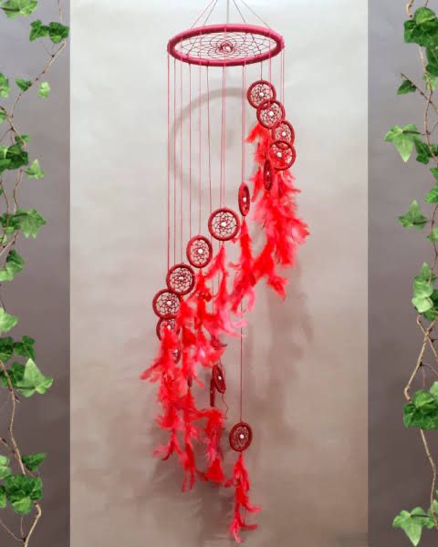 a red dream catcher hanging from a tree