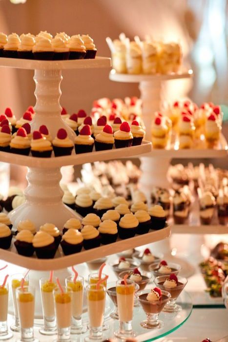 an assortment of cupcakes and pastries displayed on tiered trays at a wedding reception