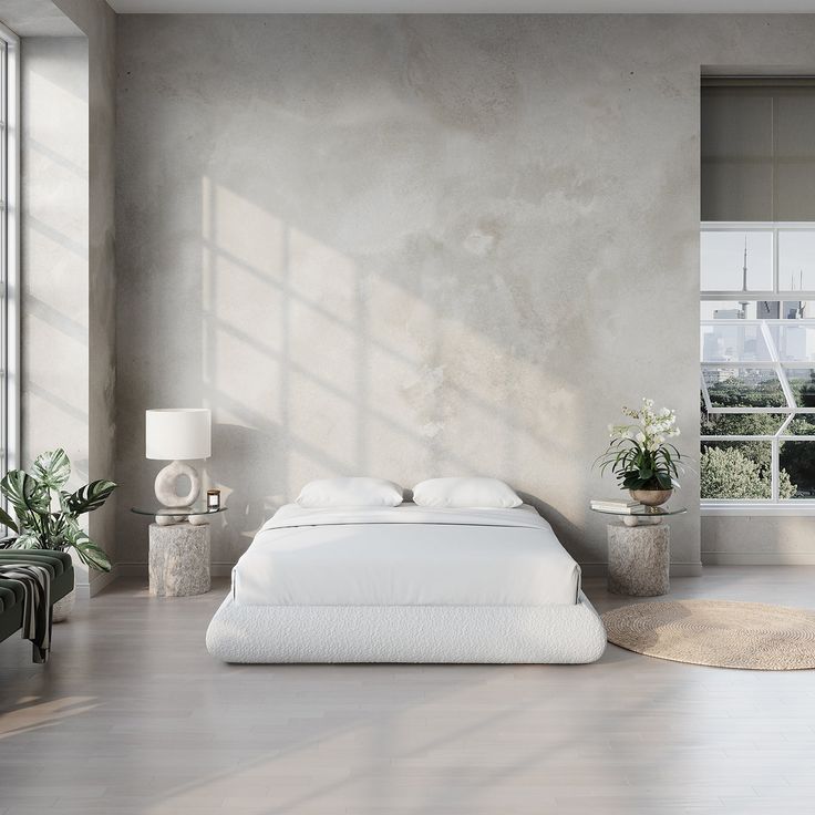 a white bed sitting in a bedroom next to a window with potted plants on it