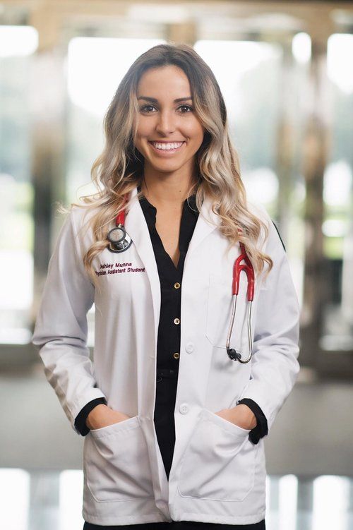 a woman in white lab coat standing with her hands on her hips and smiling at the camera