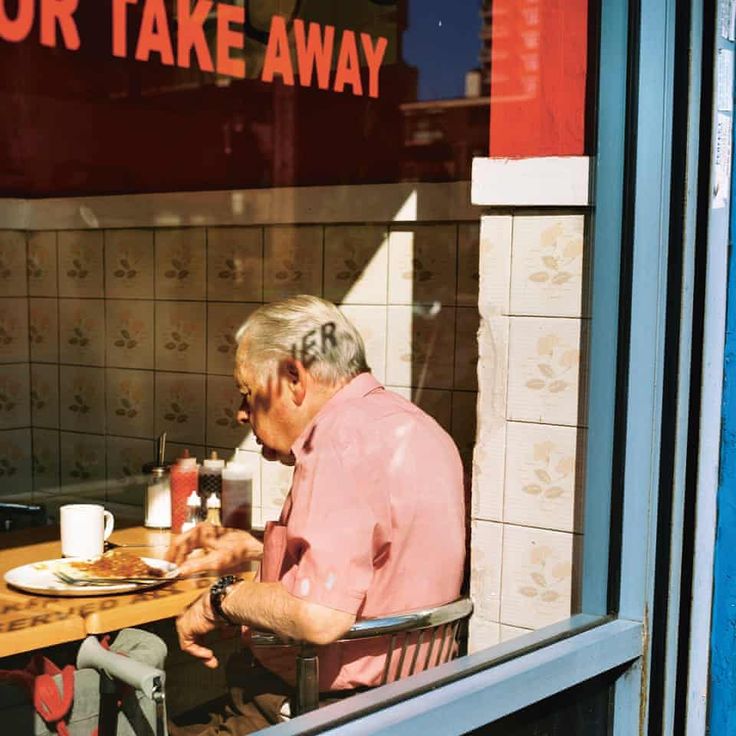 an older man sitting at a table in front of a window