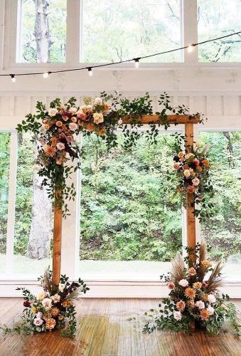 the wedding arch is decorated with flowers and greenery, along with string lights hanging from the ceiling