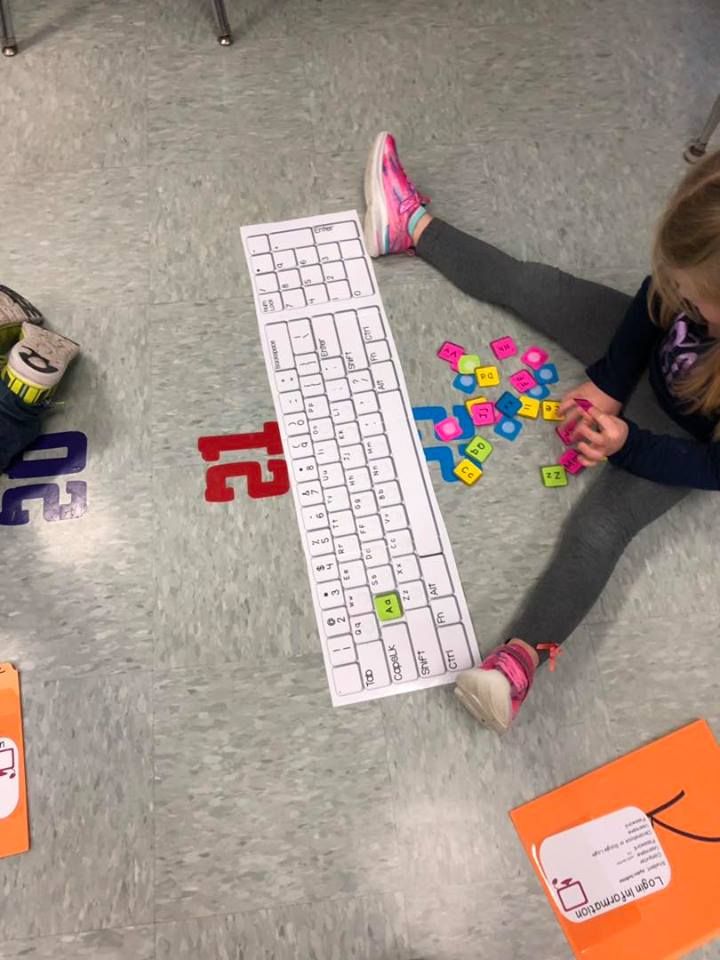 two children sitting on the floor playing with letters and numbers in front of a keyboard