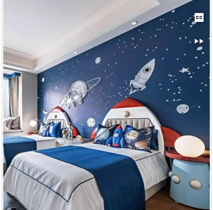 two beds in a room with blue walls and space themed wallpaper on the walls