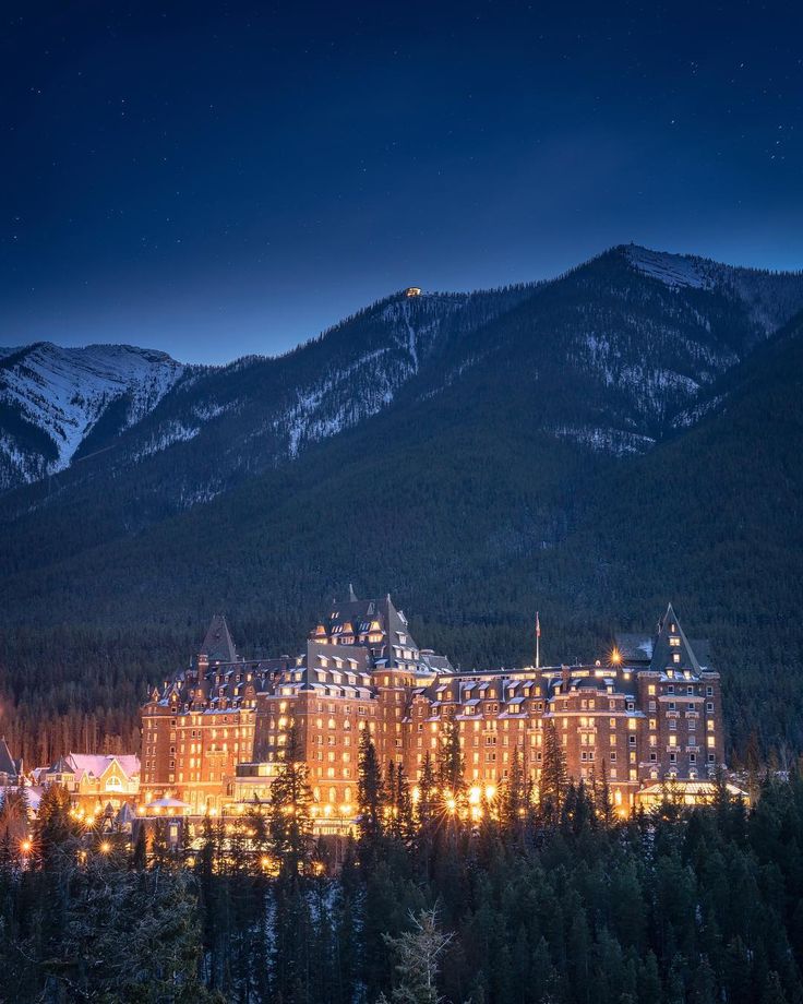 the fairmont hotel lit up at night with mountains in the background