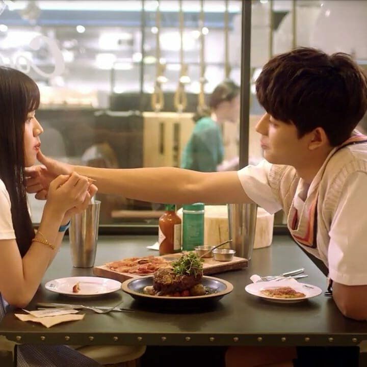 two people sitting at a table with plates of food in front of them and one person touching the other's hand