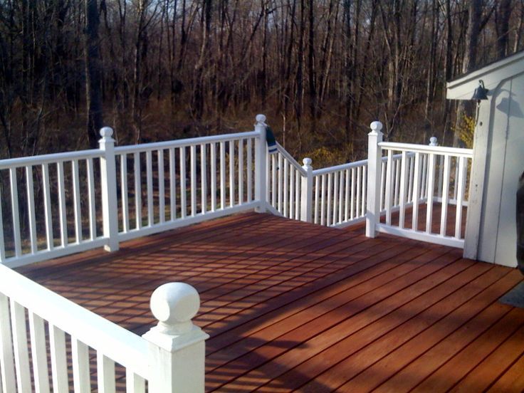 a wooden deck with white railings next to trees