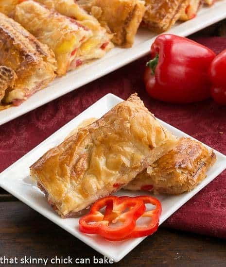 two white plates topped with pastries next to red peppers