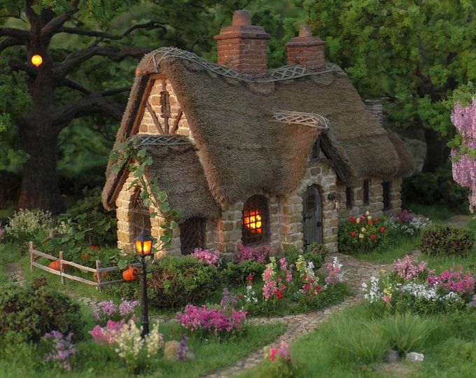 a small cottage with flowers and trees around it