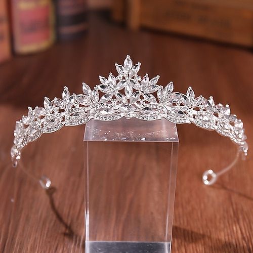 the tiara is on display in a clear box with wooden table and books behind it