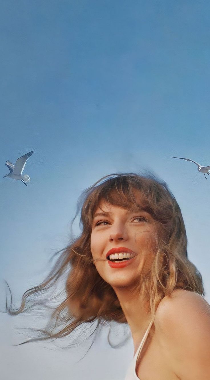 a woman with her hair blowing in the wind and seagulls flying around her