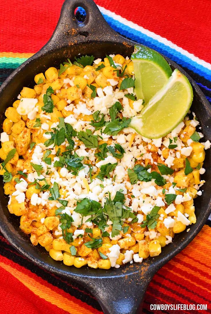 a cast iron skillet filled with corn, cheese and cilantro garnish