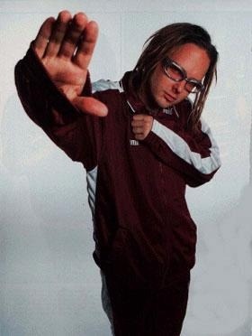 a man with long hair and glasses holding his hand up in the air while standing against a white background