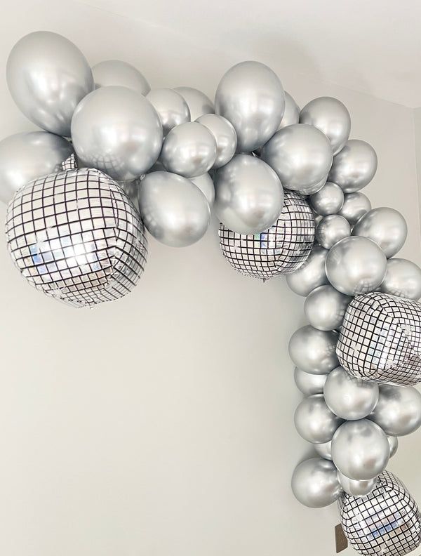 a bunch of silver balloons hanging from the ceiling