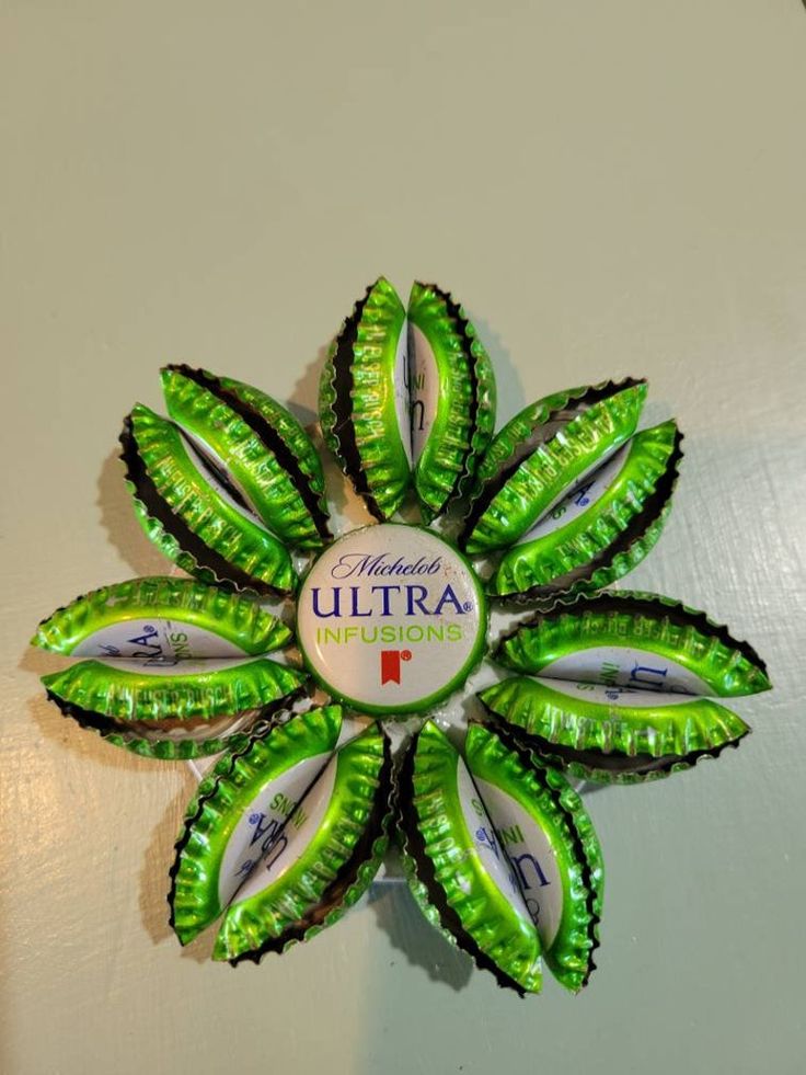 a green and white flower shaped bottle cap wall decoration with the words ultra on it