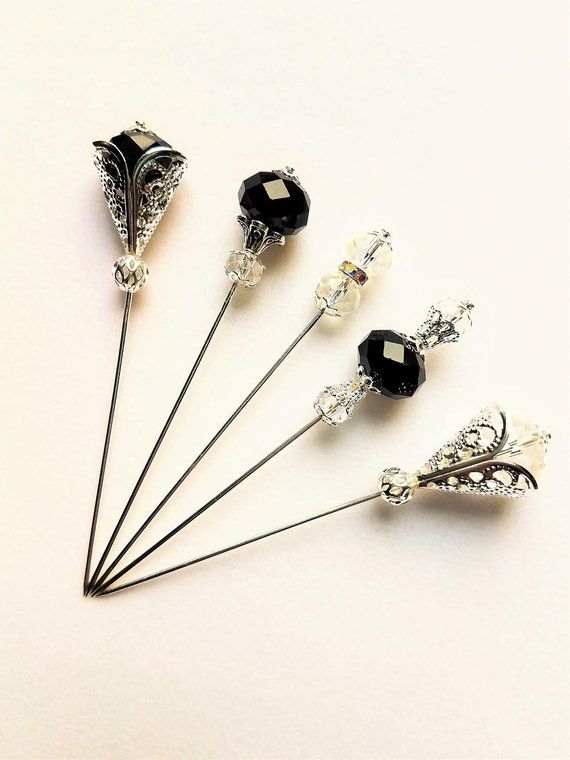 four pins with black and white crystal beads on them, all in the same design