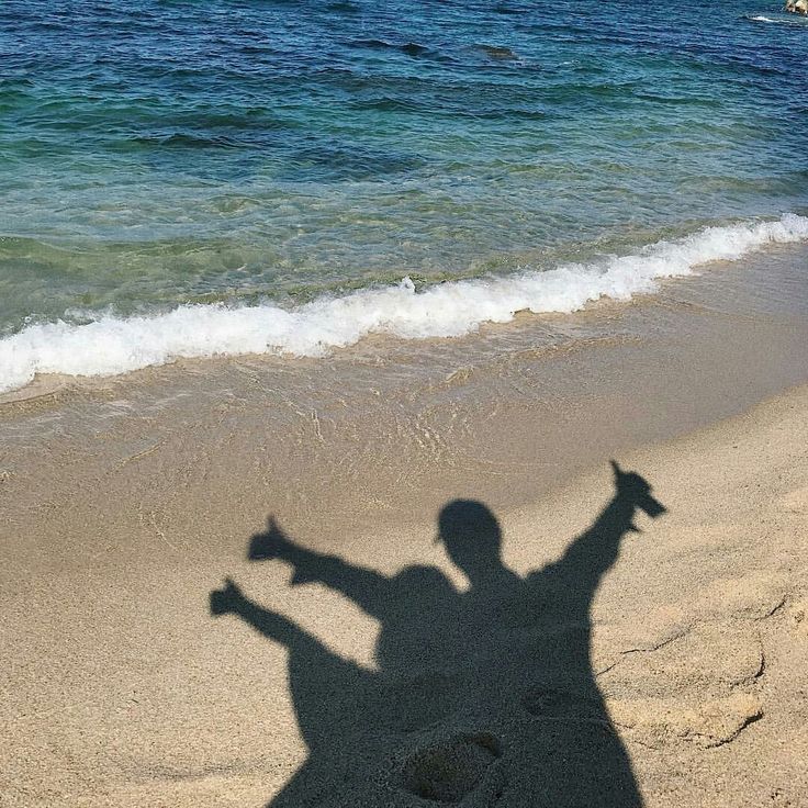 the shadow of a person standing in front of an ocean