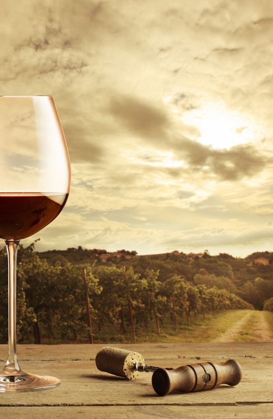 a glass of wine sitting on top of a wooden table next to a bottle and cork