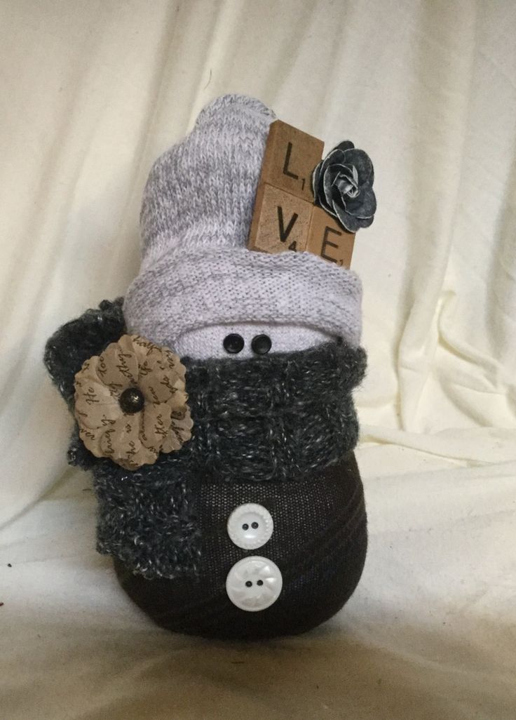 a knitted hat and scarf on top of a stuffed animal with a button in the middle