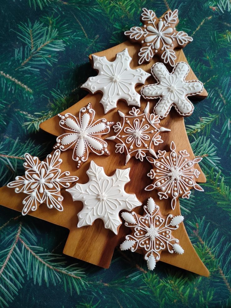 decorated cookies are arranged in the shape of a christmas tree on a wooden board with pine needles