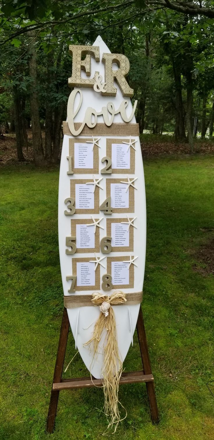 a surfboard with some writing on it sitting in the grass next to a tree